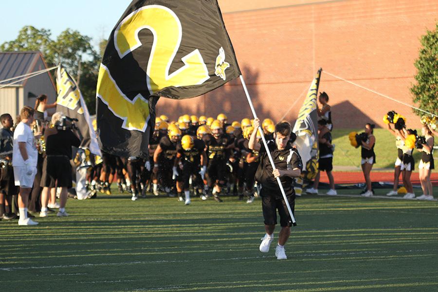 Senior Peter Dring runs the 12th Man flag before the football team.