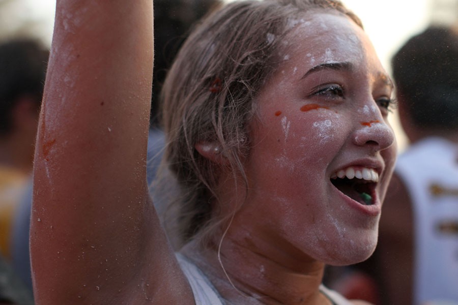 A West student watches with a smile on her face as fellow students throw muck at each other. 