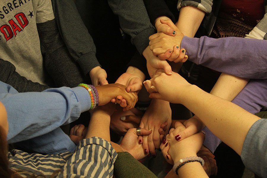 Journalism students hold hands in a team-bonding exercise called the human knot, which helped the class learn to work together to untangle themselves and improved their communication skills to help them in future class assignments. 