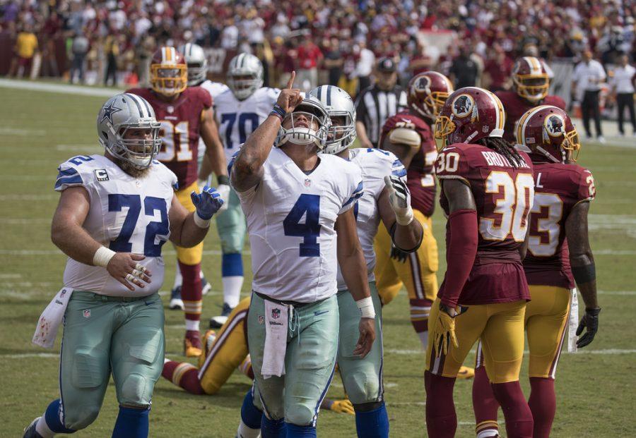 Quarterback Dak Prescott points to the sky in celebration after a nice play.