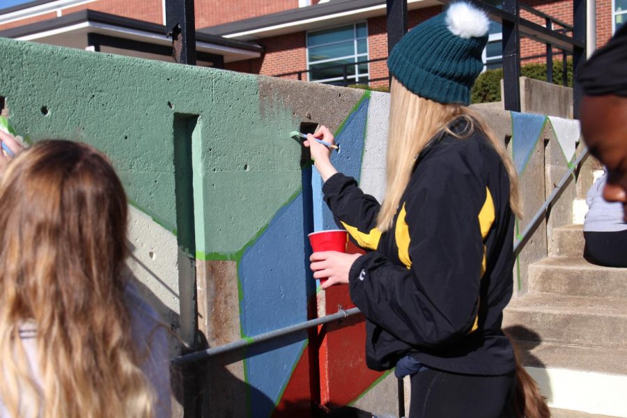 Madeline Meyer paints the wall with green paint at beautification.