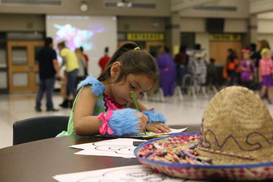 A little girl coloring a skull at the Spanish Club station.