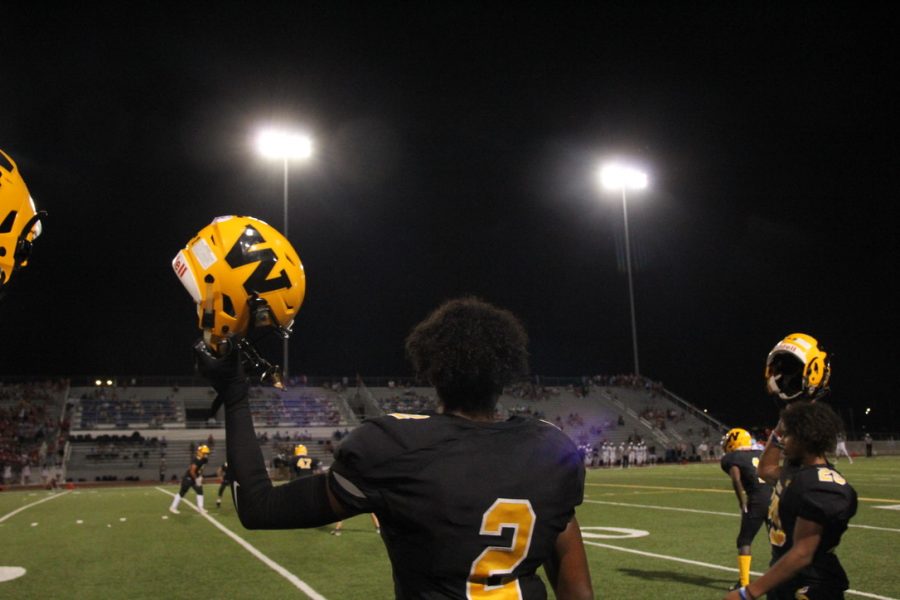 Player #2, Mehki Knight raises his helmet in support for his teammates on the field. 